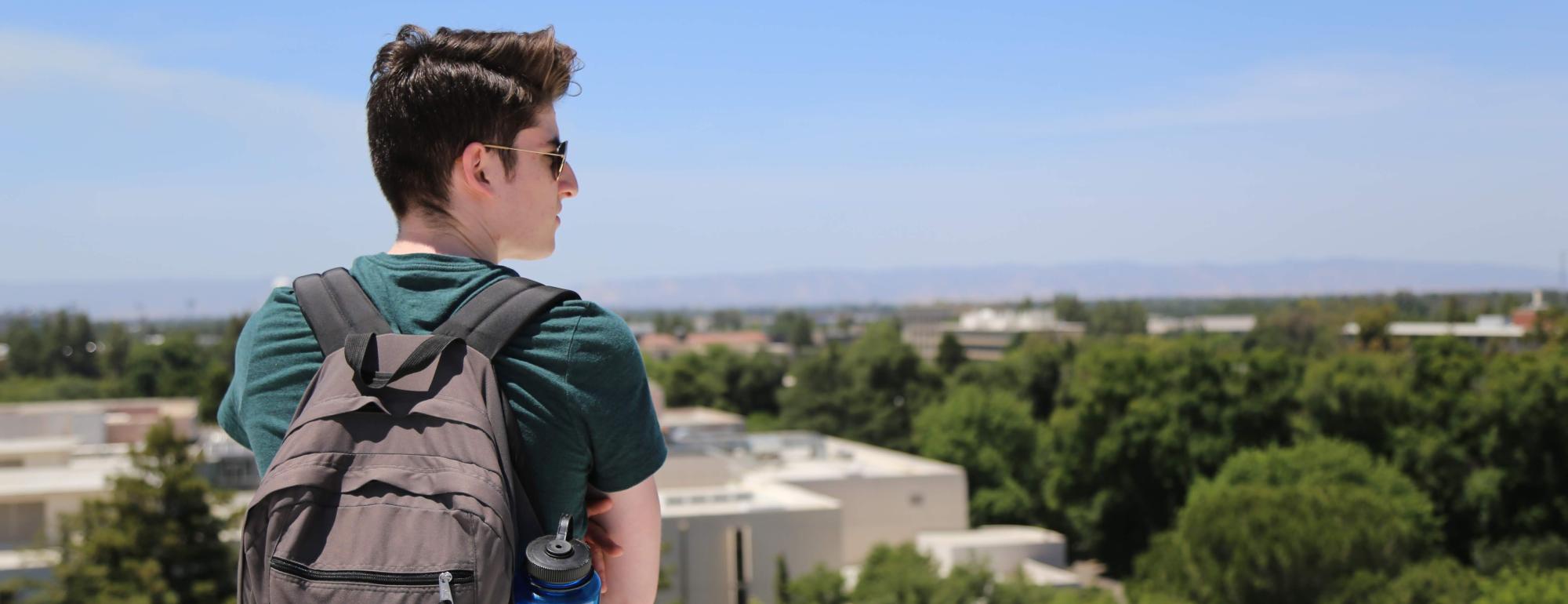 student looking off the horizon of a building roof