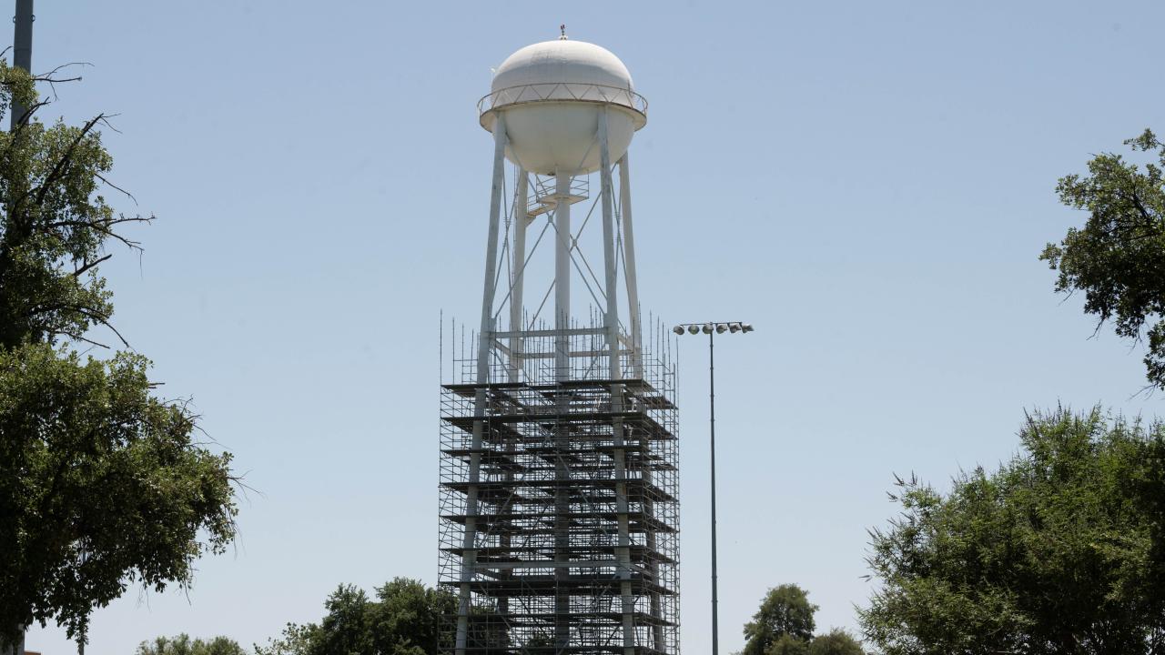 Image of a water tower on the UC Davis campus partially covered in scaffolding.