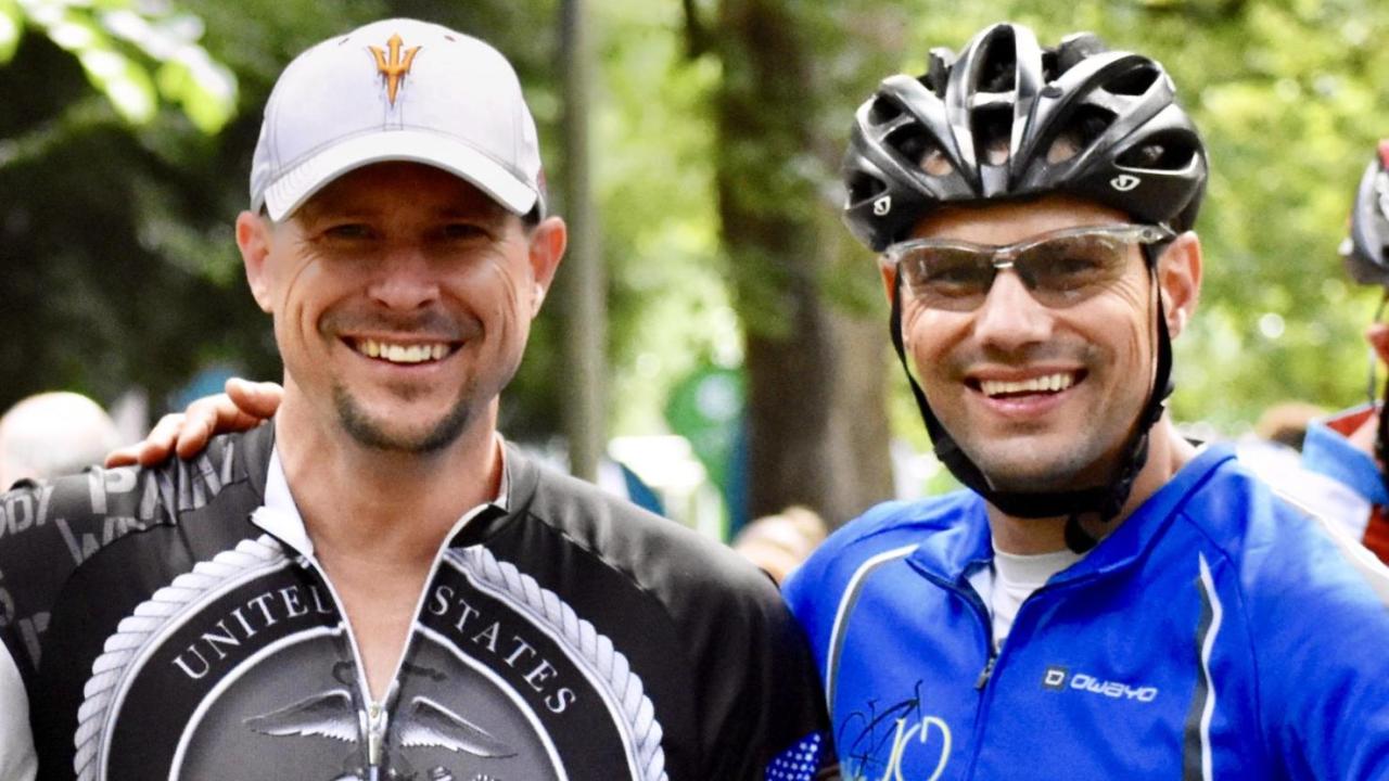 Photo of Clint Lord and his brother wearing biking gear, smiling, looking at the camera