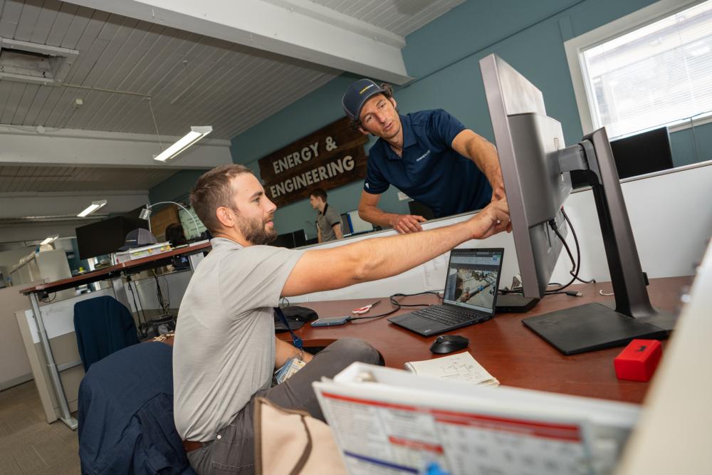 Energy Engineering team members discuss a building commissioning project, with map on computer screen