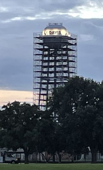Image of touchdown tower partially covered in scaffolding but with the top of the tower and UC Davis wordmark lit.