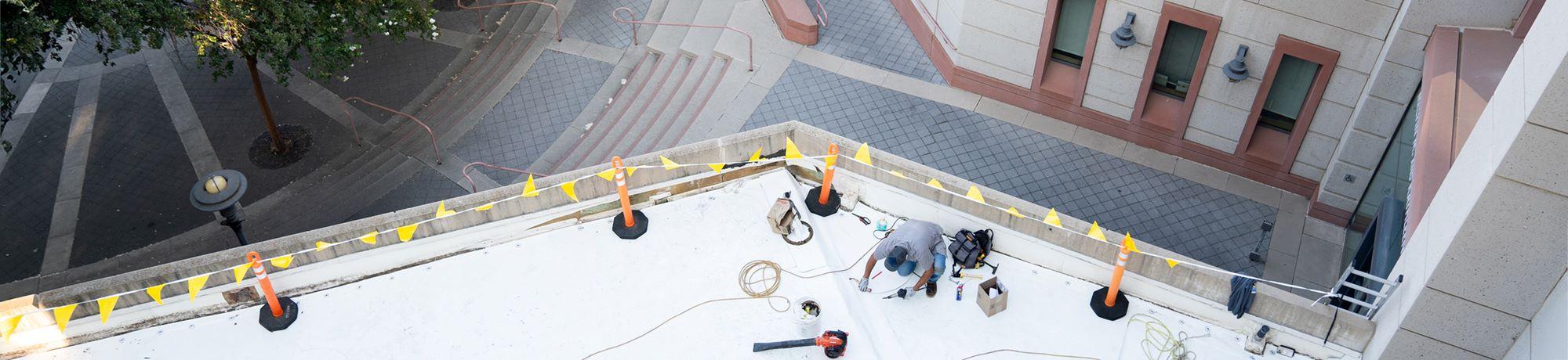 Birds eye view of facilities staff working on a roof on campus.