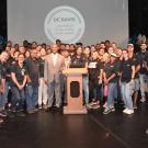 Image of a large group of UC Davis custodian staff members on stage with Chancellor May who presented them with a Citation of Excellence from UC Davis Staff Assembly.