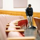 Custodian sweeps between rows of seats at a lecture hall