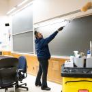 Custodian dusts above a blackboard in a classroom
